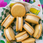 Taste Of The Masters: Make Peach Ice Cream Sandwiches 3 A basket of homemade ice cream sandwich cookies made with soft vanilla cookies and creamy peach ice cream, served on green checkered paper with Masters branding.
